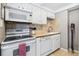 Galley kitchen features white appliances, cabinets, and a stylish backsplash above the countertops at 160 Jackson St # 5, Denver, CO 80206
