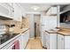 Galley kitchen features white appliances, cabinets, and a stylish backsplash above the countertops at 160 Jackson St # 5, Denver, CO 80206