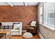 Cozy living room with exposed brick wall, wood floors, and comfortable seating next to the window with natural light at 160 Jackson St # 5, Denver, CO 80206