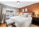 Stylish bedroom featuring a brick accent wall, comfortable furniture, and natural light at 160 Jackson St # 5, Denver, CO 80206