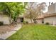 Inviting townhouse exterior featuring a well-manicured lawn, pathway, and mature trees and shrubs at 2459 S Xanadu Way # B, Aurora, CO 80014