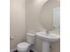 Powder room featuring a modern pedestal sink, toilet, and large round mirror at 1456 Sepia Ave, Longmont, CO 80501