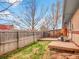 Small backyard with grass, wood fence, deck, central air unit, and brick exterior at 4201 Shoshone St, Denver, CO 80211