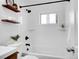 Bright bathroom showcases a white tub with black fixtures, shelving, and fresh white tile at 4201 Shoshone St, Denver, CO 80211