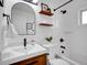 Bright bathroom features a modern vanity, an arched mirror, and a shower with black fixtures at 4201 Shoshone St, Denver, CO 80211
