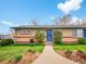 Charming single-story brick home with a well-manicured lawn and inviting blue entry door under a partly cloudy sky at 4201 Shoshone St, Denver, CO 80211
