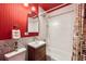 Modern bathroom features red accent wall, updated fixtures, new vanity, tile flooring and tub shower at 7991 Stuart St, Westminster, CO 80030