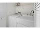 Bright laundry room with a white washer and dryer set and overhead shelving at 4747 S Balsam Way # 104, Littleton, CO 80123