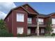Multi-story home with dark red siding, stone accents, and a covered balcony and patio at 917 W 129Th Pl, Denver, CO 80234