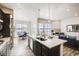 Bright kitchen island with stainless steel sink, dark cabinets, and open dining and living area at 917 W 129Th Pl, Denver, CO 80234