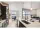Bright kitchen island with stainless steel sink, dark cabinets, and open dining and living area at 917 W 129Th Pl, Denver, CO 80234