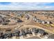 Aerial view of a suburban neighborhood showcasing winding streets, residential homes, and open fields at 6664 Merrimack Dr, Castle Pines, CO 80108