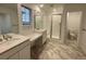 Bright bathroom with double sink vanity, tiled floors, and glass-enclosed shower at 687 Raindance St, Erie, CO 80516
