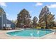 Community swimming pool with clear blue water, lounge chairs, trees, and building in the background at 7220 S Gaylord St # G17, Littleton, CO 80122