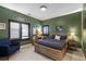 Comfortable green bedroom features a natural wood bed frame, wooden desk, and shuttered windows at 948 Buffalo Ridge Rd, Castle Pines, CO 80108