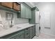 Well-organized laundry room with green cabinetry, white countertops, and a stacked washer and dryer at 948 Buffalo Ridge Rd, Castle Pines, CO 80108