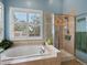 Bright bathroom features a soaking tub beneath a window and a glass-enclosed shower stall at 5660 S Eaton St, Littleton, CO 80123