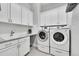 Well-lit laundry room featuring modern washer and dryer, ample counter space, and storage cabinets at 27655 E Moraine Dr, Aurora, CO 80016