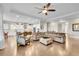 Bright, open-concept living room flowing into a modern kitchen, featuring a ceiling fan and hardwood floors at 27655 E Moraine Dr, Aurora, CO 80016
