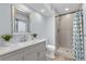 Bathroom boasts a modern vanity with a sink, decorative mirror and tiled shower with blue patterned shower curtain at 13052 W Asbury Pl, Lakewood, CO 80228