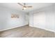 Bright empty bedroom features a ceiling fan, updated flooring, closet space and artwork at 13052 W Asbury Pl, Lakewood, CO 80228
