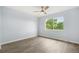 Bright empty bedroom features a ceiling fan, updated flooring and a large window overlooking a lush green yard at 13052 W Asbury Pl, Lakewood, CO 80228