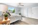 Bright bedroom features updated flooring, a ceiling fan, and a large window overlooking a lush green yard at 13052 W Asbury Pl, Lakewood, CO 80228