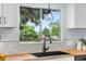 Close-up of kitchen featuring a black sink, butcher block counters, updated fixtures, and view from the window at 13052 W Asbury Pl, Lakewood, CO 80228