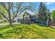 Inviting blue home with a charming front porch and lush green lawn under the shade of mature trees, creating a welcoming curb appeal at 8370 W Evans Pl, Lakewood, CO 80227