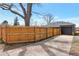 Backyard view featuring a new fence, mature tree, and one-car garage with an updated door at 1320 Locust St, Denver, CO 80220