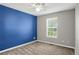 Sunny bedroom with a large window, neutral carpet, ceiling fan, and blue accent wall at 8835 Edinburgh Cir, Highlands Ranch, CO 80129