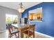 Bright dining room features wood table, chairs, blue accent wall, and natural light from a sliding glass door to a balcony at 8835 Edinburgh Cir, Highlands Ranch, CO 80129