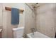 A bath/shower area in a bathroom featuring tan tile walls, a white toilet, and a shower head at 4117 S Mobile Cir # C, Aurora, CO 80013