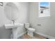 Bright bathroom with a modern pedestal sink, round mirror and new toilet at 5722 Farrier Pt, Castle Rock, CO 80104