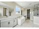 Bright bathroom featuring dual vanities, soaking tub, and a marble shower at 5722 Farrier Pt, Castle Rock, CO 80104