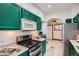 Modern kitchen featuring stainless steel appliances, gas range, microwave, and green cabinetry at 320 E Dakota Ave, Denver, CO 80209