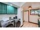 Bright laundry area with side-by-side washer and dryer and upper green cabinets at 320 E Dakota Ave, Denver, CO 80209