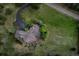 Aerial view of a brown roofed home with stone accents, patio, and landscaping surrounded by green lawns at 2191 Baldy Ln, Evergreen, CO 80439