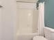 Bright bathroom featuring a white tiled tub, shower with curtain, and a teal accent wall at 8322 S Upham Way, Littleton, CO 80128
