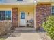 Inviting front porch with brick accents, a chair, and well-maintained landscaping for welcoming curb appeal at 8322 S Upham Way, Littleton, CO 80128