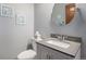 Charming powder room with gray walls, framed artwork, and a round mirror over the vanity at 1121 W Kettle Ave, Littleton, CO 80120