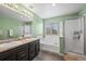 Bright bathroom features a double vanity, bathtub, and glass-enclosed shower, providing a fresh and clean space at 4797 Longs Peak St, Brighton, CO 80601