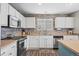 Well-lit kitchen with modern white cabinetry, stainless steel appliances, and stone backsplash, offering style and functionality at 4797 Longs Peak St, Brighton, CO 80601