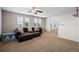Spacious carpeted living area with a sectional couch and bright natural light from the large window at 4797 Longs Peak St, Brighton, CO 80601