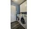 Modern laundry room with stainless steel washer and dryer, storage cabinets and hardwood floors at 14873 E 119Th Ave, Commerce City, CO 80603