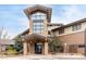 Inviting building entrance with stone pillars, well-lit walkway and well maintained landscaping in winter at 14050 E Linvale Pl # 309, Aurora, CO 80014