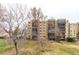 Exterior shot showcasing the building's architecture and mature trees against a lush lawn at 14050 E Linvale Pl # 309, Aurora, CO 80014