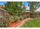 Manicured backyard featuring a wooden fence, mature trees, and a garden bed with rose bushes at 17372 E Prentice Cir, Centennial, CO 80015