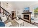 Cozy living room featuring a brick fireplace, dark wood floors, and staircase access to upper levels at 517 Chiswick Cir, Highlands Ranch, CO 80126