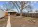 Backyard with a large tree next to a single story house with a walkway and a wooden fence providing privacy at 3550 Fairfax St, Denver, CO 80207